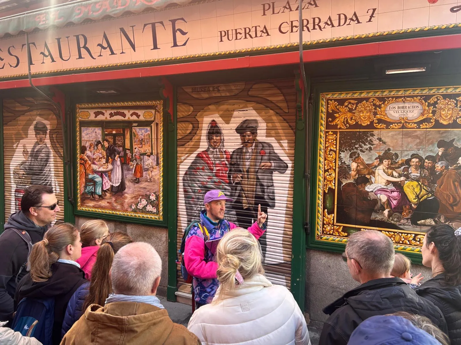 Lucas, guide francophone, commente une façade d'azulejos de la Plaza Puerta Cerrada devant un groupe de visiteurs à Madrid