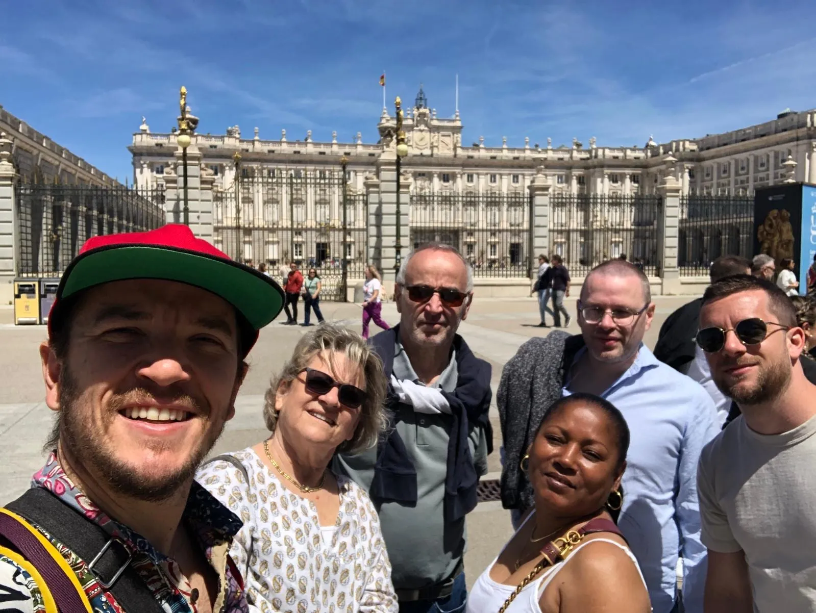 Lucas et un groupe de visiteurs devant la façade du Palais Royal de Madrid par temps ensoleillé