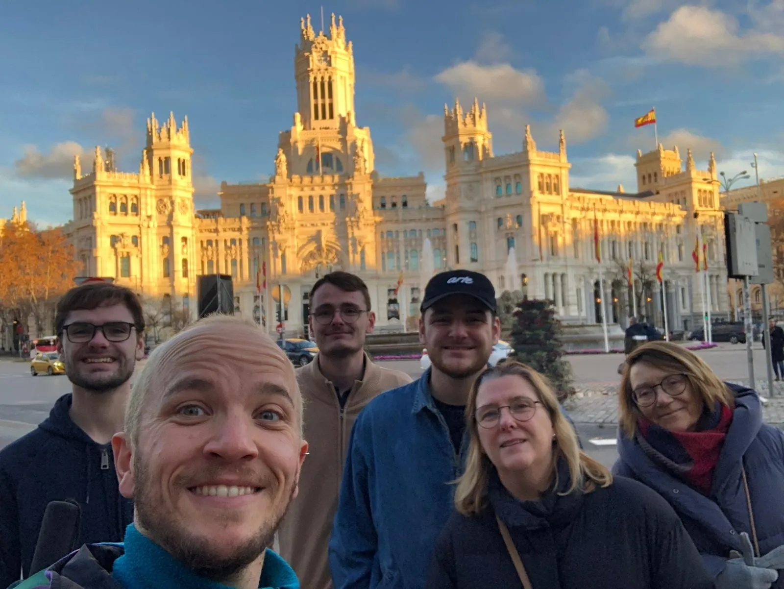 Lucas et son groupe de visiteurs francophones posant devant le Palacio de Cibeles, illuminé par le soleil couchant